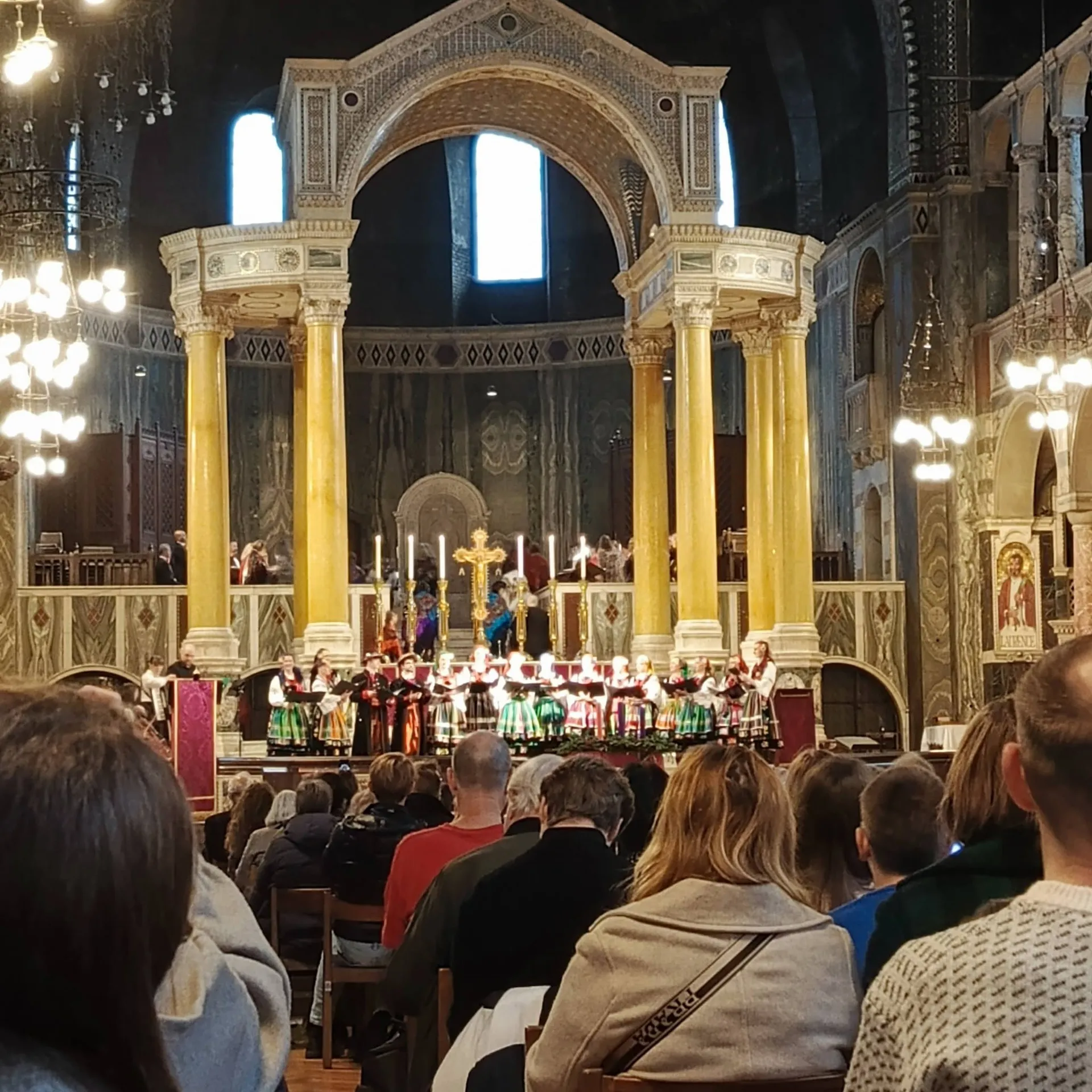 Wnętrze Westminster Cathedral podczas koncertu kolęd: chór przy ołtarzu i publiczność w ławkach.