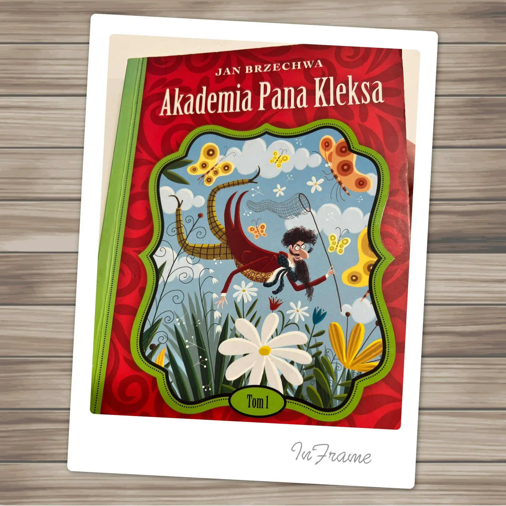 Okładka powieści Jana Brzechwy „Akademia pana Kleksa” z baśniową ilustracją kwiatów i motyli.